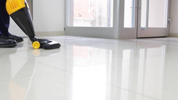 A man cleaning the white floor with the vacuum cleaner - Φωτογραφία, εικόνα