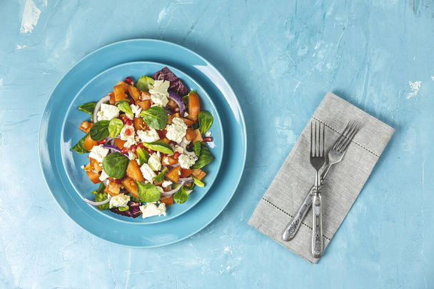 Sininen lautanen tuoretta superruokaa terveellistä salaattia punasipulia, tomaatteja, doucette (karitsasalaattia, maissisalaattia, peltosalaattia) ja fetajuustoa. Vaaleansininen pinta, ruokailuvälineet, ylhäältä katsottuna, tasainen lay, kopiotila
. - Valokuva, kuva