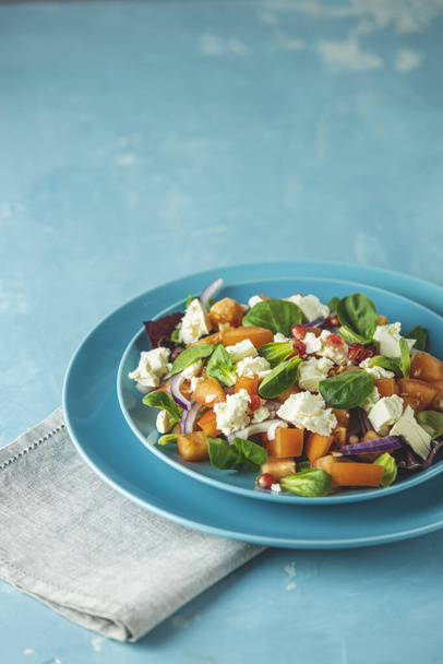 Blauwe plaat verse superfoods gezonde salade met rode ui, tomaten, doucette (lamssla, maïssalade, veldsalade) en feta kaas. Lichtblauw oppervlak - Foto, afbeelding