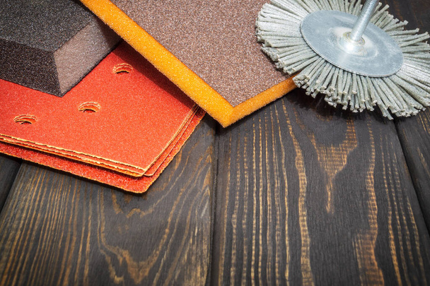 Set van schurende gereedschappen en bruin schuurpapier op een zwarte vintage houten planken tovenaar wordt gebruikt voor het slijpen van items - Foto, afbeelding