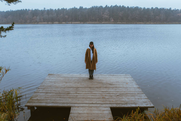 Φθινόπωρο λίμνη σεζόν γυναίκα σε παλτό σε ξύλινη προβλήτα πτώση - Φωτογραφία, εικόνα