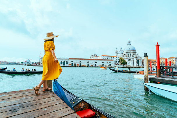 woman in yellow summer dress walking by Venice looking at grand canal vacation concept - Photo, Image