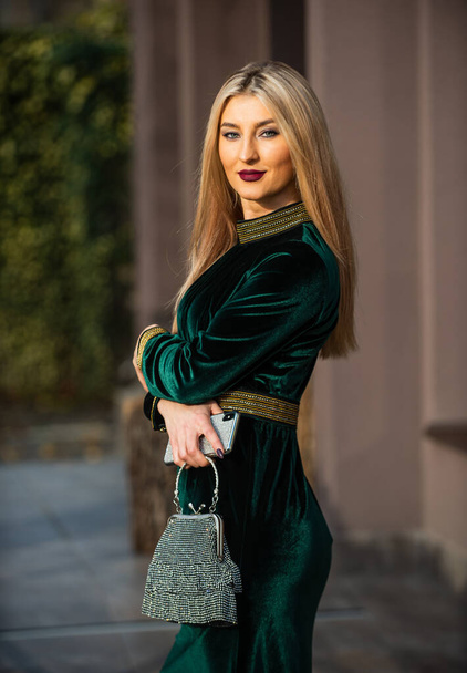 Perfect female. glam clutch accessory. elegant woman in green velour dress. glamour velvet textile. sexy businesswoman outdoor. modern life. blonde girl care gem stone handbag or purse - Foto, imagen