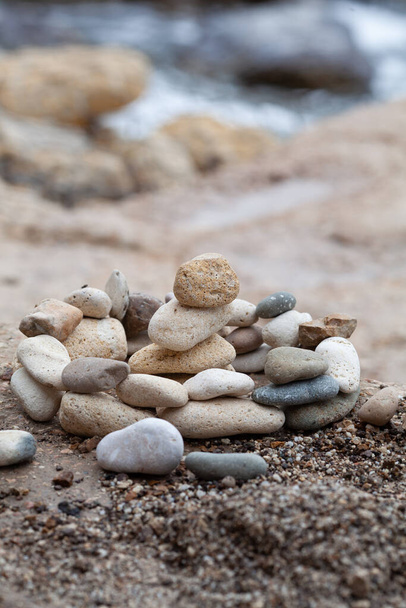 Steine türmen sich mit verschwommenem Meereshintergrund auf. Pyramide rechts. - Foto, Bild
