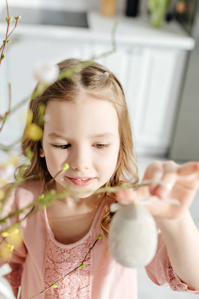 selective focus of cute kid near willow brunches with decorative easter egg - Photo, Image