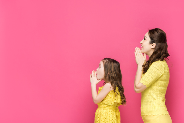 profile of mother and daughter with praying hands isolated on pink  - Фото, изображение