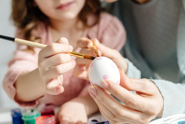 cropped view of mother and daughter painting easter egg  - Fotografie, Obrázek