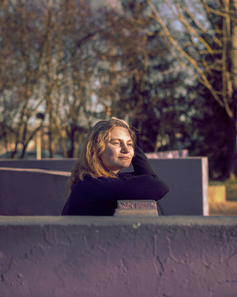 blonde girl with blue eyes with purple wall as background in a park in a winter sunny afternoon - Φωτογραφία, εικόνα