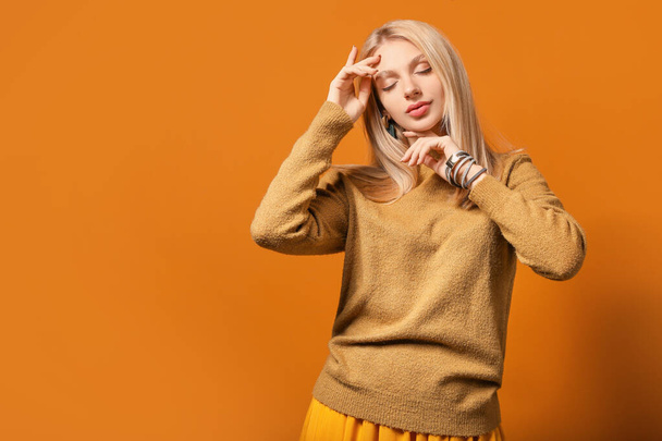 Young woman in warm sweater on color background - Valokuva, kuva