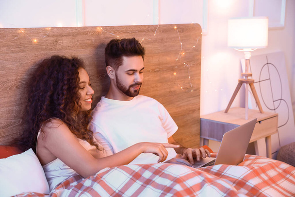 Happy young couple watching movie in bedroom - Photo, Image