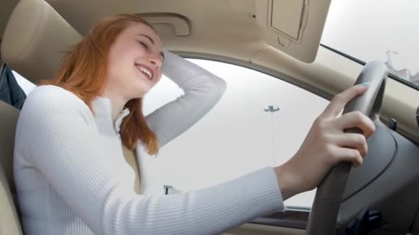 Νεαρή γυναίκα οδηγός διασκεδάζει πίσω από το τιμόνι ακούγοντας μουσική σε ένα αυτοκίνητο. - Πλάνα, βίντεο