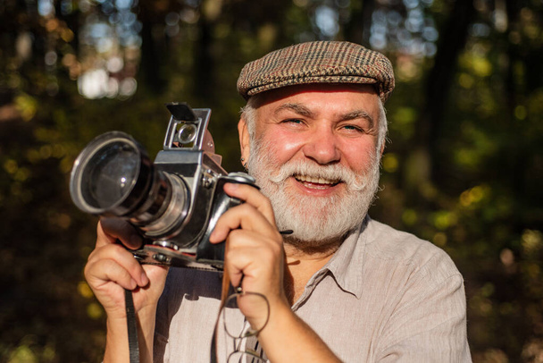 Vintage style. Travel Lifestyle vacations concept. Man photographer holding a vintage camera. Bearded man. Lifestyle and travel concept. Give me a smile. The concept of macro nature photography - Foto, Imagen
