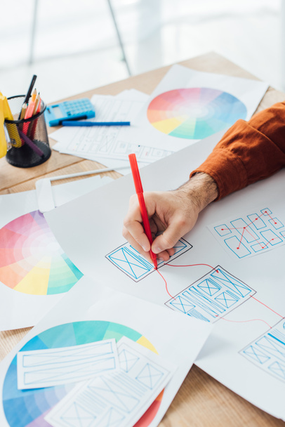 Cropped view of designer with marker developing user experience design with templates and color circle on table - Photo, Image