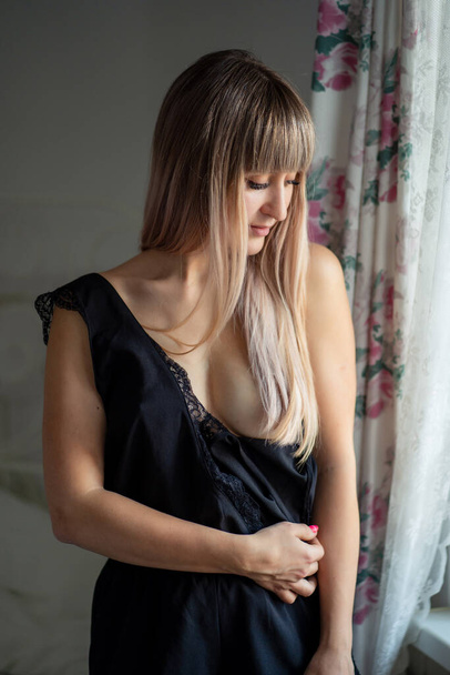Blonde girl with black lingerie bares breast. - Фото, изображение