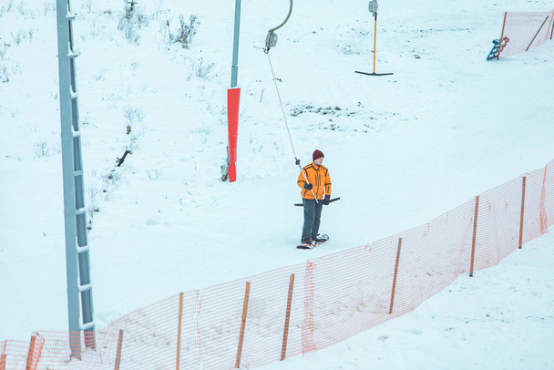 hombre en snowboard usando yugo de elevación para llegar al pico de la colina. actividades de invierno
 - Foto, imagen