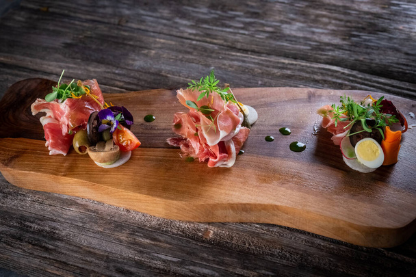 cold cuts of prosciutto with vegetables and eggs on wooden cutting board - Valokuva, kuva
