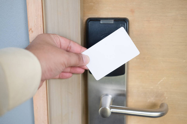 男の手はホテルの部屋のドアを開くためにキーカードスイッチを使用します。ドアのロックとロックを解除するドアのアクセス制御スキャンキーカード用の磁石カードを保持 - 写真・画像
