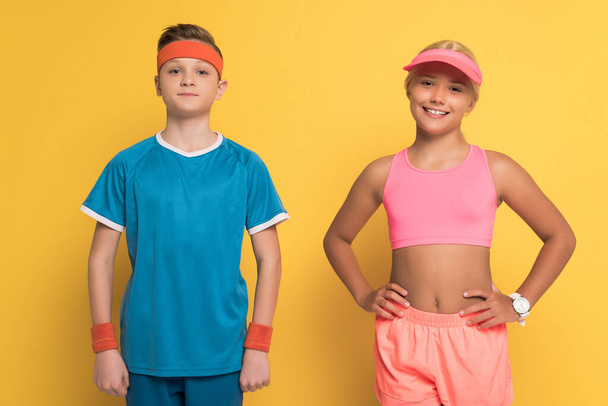 smiling kids in sportswear looking at camera on yellow background  - Zdjęcie, obraz
