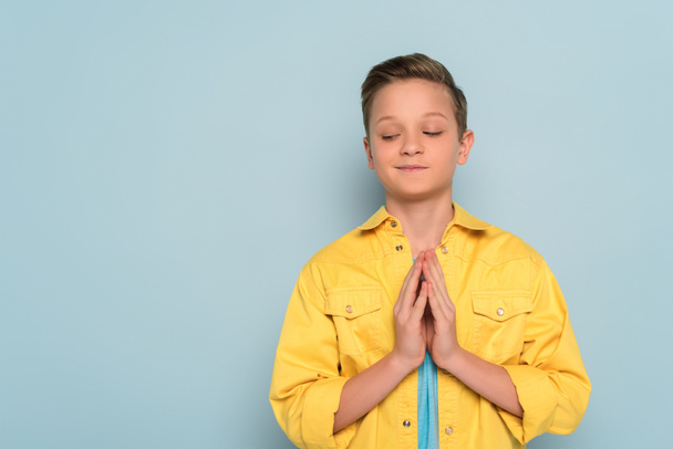 mosolygós és aranyos gyerek bemutató imádkozó kezét kék háttér  - Fotó, kép