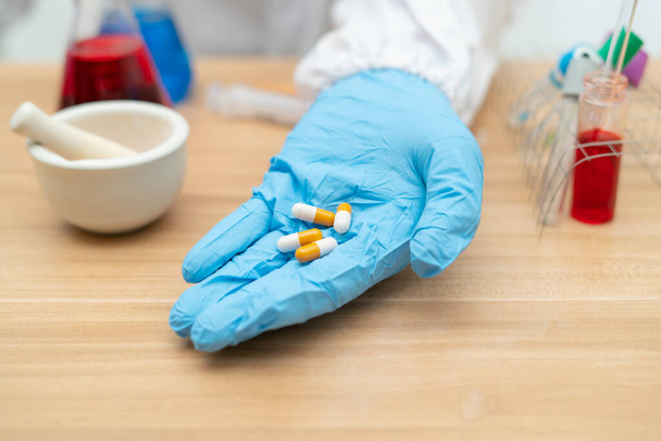 Tabletit kapselit laboratorioissa työskentelevien tutkijoiden käsissä
 - Valokuva, kuva
