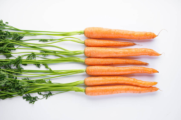 Tasainen lay koostumus kypsä tuoreita porkkanoita valkoisella pohjalla
 - Valokuva, kuva