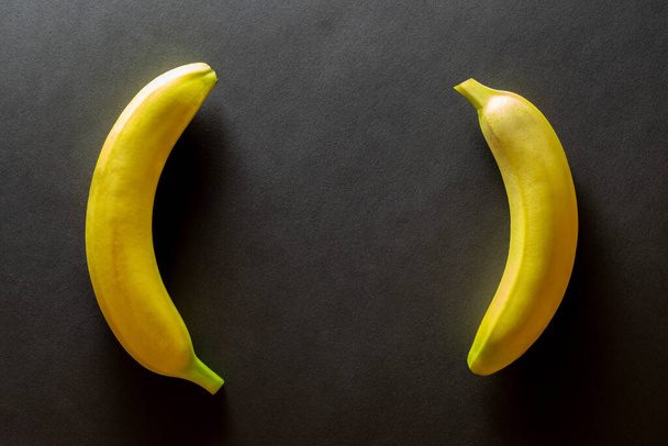 Žluté pozadí designu. Banány izolované na černém s kopírovacím prostorem. Pohled shora. - Fotografie, Obrázek