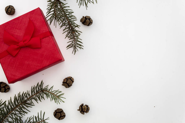 Composición creativa Útil para la tarjeta de felicitación de Navidad y Año Nuevo Creado con caja de regalo roja, ramas de pino verde y pequeños conos de pino. Copiar espacio en el lado derecho
 - Foto, imagen