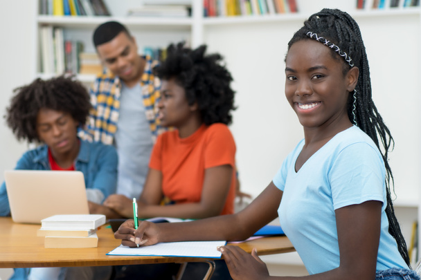 Γελώντας αφροαμερικανός νεαρός ενήλικας με φόβο και ομάδα μαθητών στην τάξη του πανεπιστημίου - Φωτογραφία, εικόνα