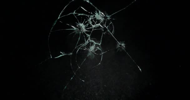 Broken cracks glass fracture effect texture isolated abstract black background. Bullet cracked window with big hole screen mirror weapon shot. - Footage, Video