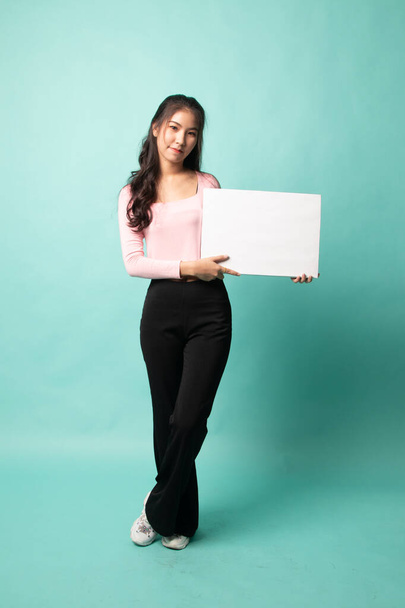 Full body of young Asian woman with white blank sign on cyan background - Фото, изображение