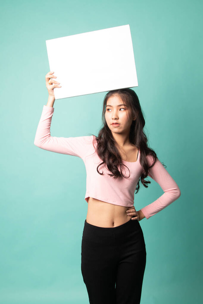 Young Asian woman with white blank sign on cyan background - Photo, image