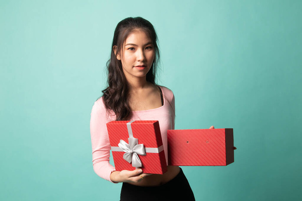 Young Asian woman open a golden gift box on cyan background - Foto, afbeelding