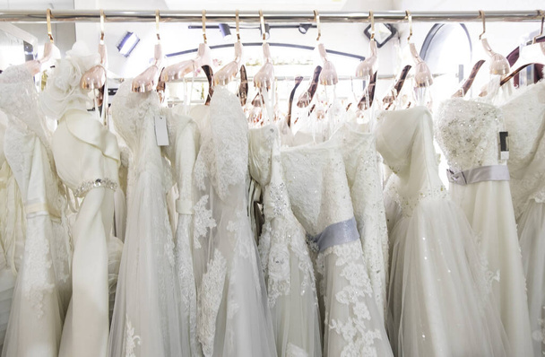 Beautiful, White bridal dress texture on background. Wedding dresses hanging on a hanger interior of bridal salon. Design, fashion modern luxury in detail. - Fotografie, Obrázek