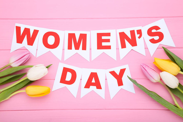 Text Womens Day with tulip flowers on pink wooden table - Fotó, kép