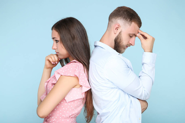 Young upset couple standing by the back to each other on blue background - Foto, immagini