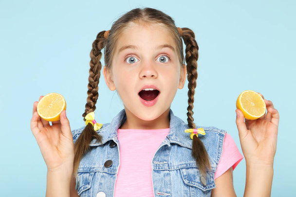 Young girl with lemon fruit on blue background - 写真・画像