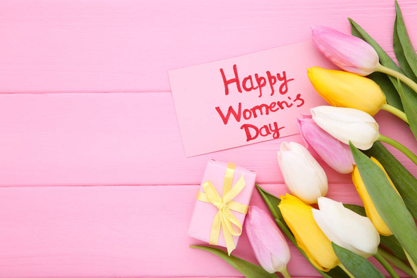 Text Happy Womens Day with tulip flowers and gift box on wooden table - 写真・画像