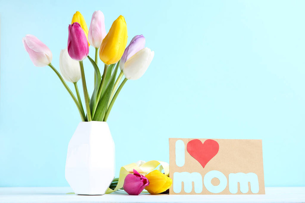 Bouquet of tulip flowers in vase with text I Love Mom on blue background - Photo, image