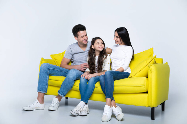 portrait of happy young family sitting on yellow sofa - Zdjęcie, obraz