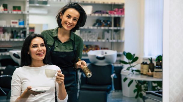 Female hairdresser smiling, making hairstyle to young woman in beauty salon - Fotoğraf, Görsel