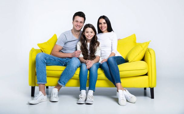 portrait of happy young family sitting on yellow sofa - Foto, imagen