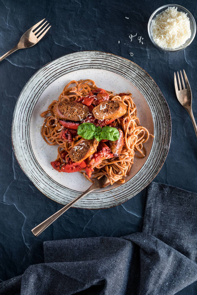 Top down view of a plate of gourmet red pepper pasta topped with chorizo sausage ready for eating. - Fotografie, Obrázek