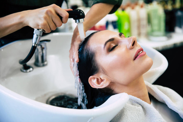 Hairdresser washing head her client. Woman in a hair salon - Φωτογραφία, εικόνα