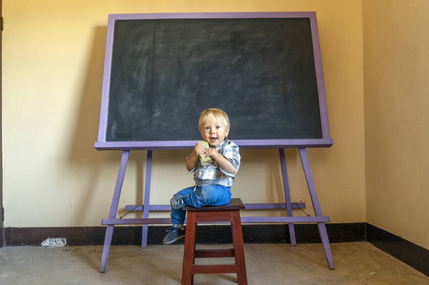 Sevimli sarışın çocuk tahtasında süngerle oturuyor.  - Fotoğraf, Görsel