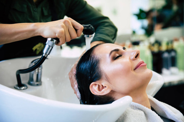Hairdresser washing head her client. Woman in a hair salon - Valokuva, kuva