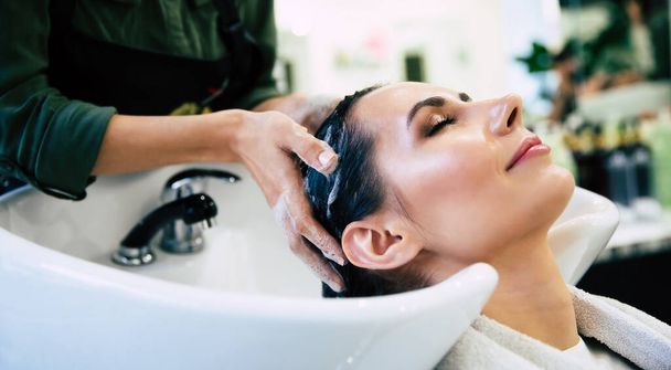 Hairdresser washing head her client. Woman in a hair salon - Φωτογραφία, εικόνα