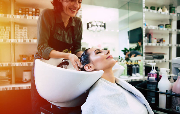 Fryzjer myje głowę swojemu klientowi. Kobieta w salonie fryzjerskim - Zdjęcie, obraz