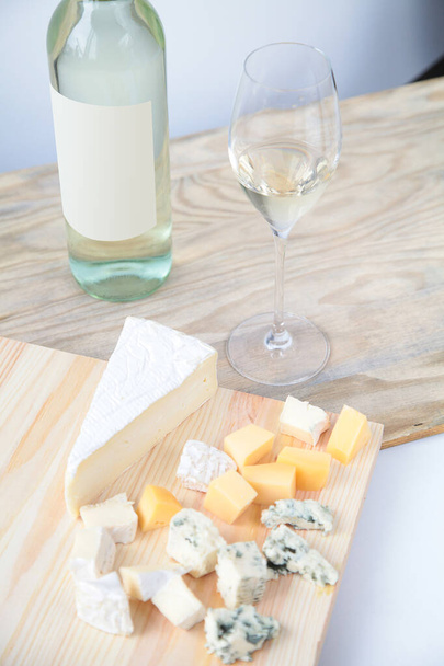 Botella de vino blanco y copas de vino, queso sobre fondo de madera
 - Foto, Imagen