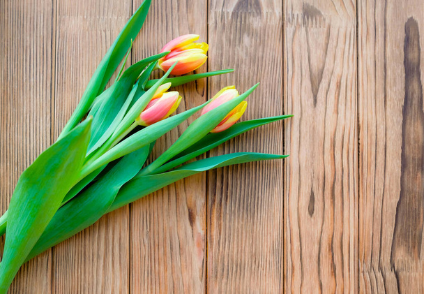 Tulipány 8. března. Růžové a žluté pupeny na dřevěném pozadí. Místo pro text. - Fotografie, Obrázek