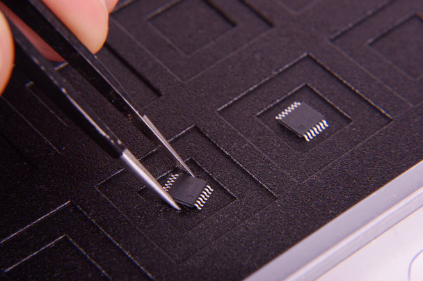 Technologia Tiny Smt komponent elektroniczny chip i inżynier trzymając go z pęsetą - Zdjęcie, obraz